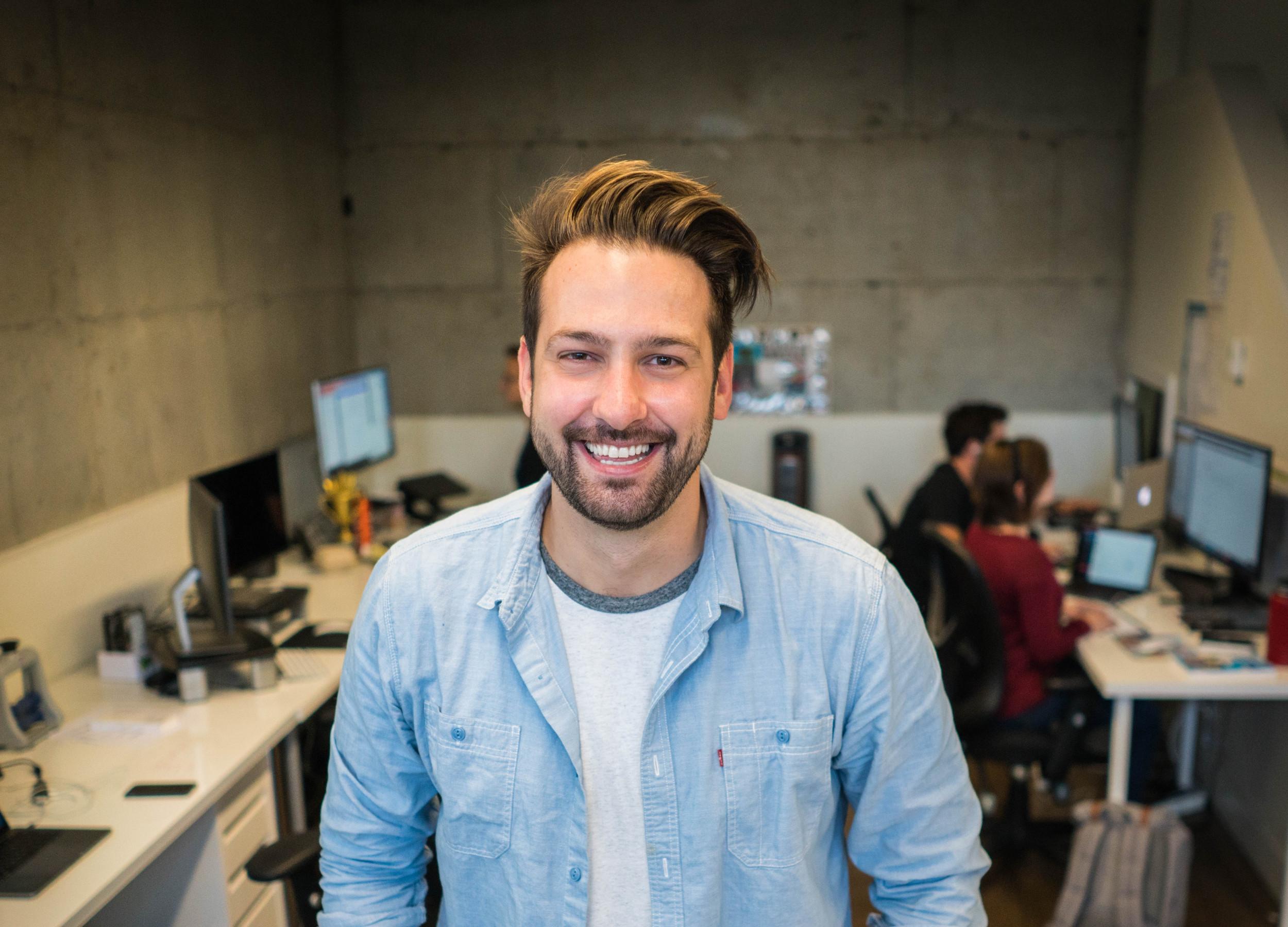 Junger Mann in Gemeinschaftsbüro, schaut in die Kamera