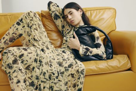 Frau mit gemustertem Kleid auf einer gelben Ledercouch