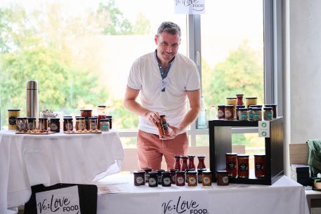 junger Mann präsentiert seine Produkte am Stand