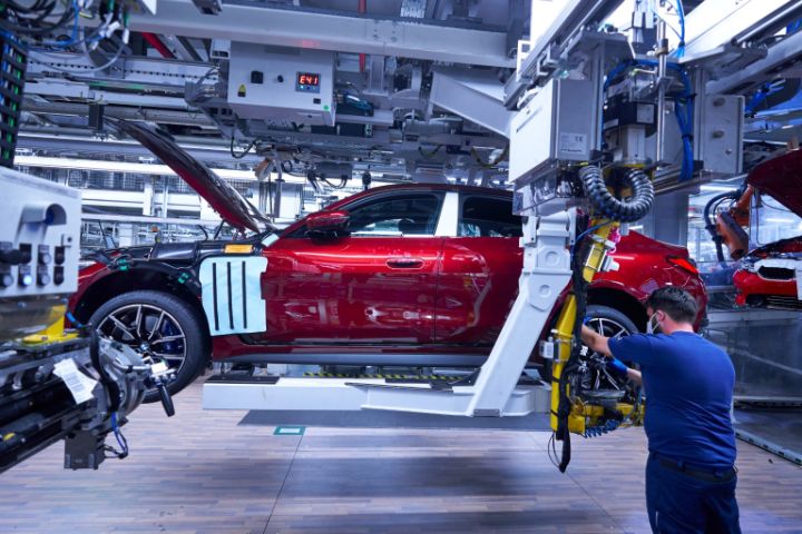 BMW Werk München - Monteur fixiert Reifen an rotem BMW i4