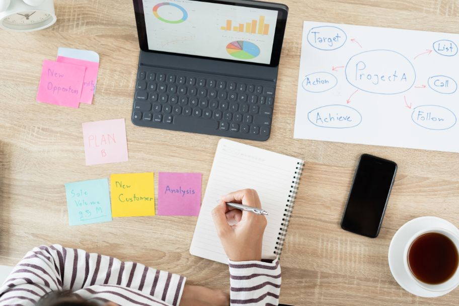 Gründer*in sitzt am Schreibtisch mit Block und Laptop