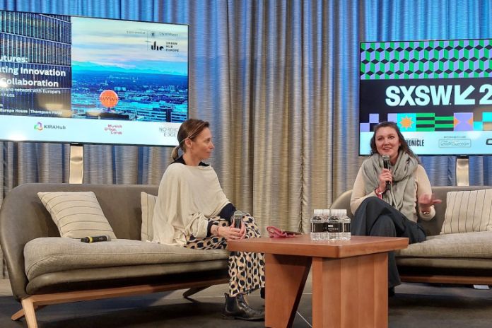 SXSW - München Panel © munich business zwei Frauen im Interview, im Hintergrund ein Slide vom Innovation Hub Munich