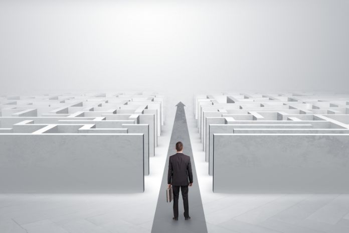 Mann mit Aktentasche steht vor einem Labyrinth, aber vor ihm tut sich ein gerader Weg auf