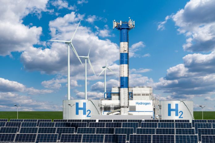 Wasserstofftanks, Windräder, Solarmodule zusammen gruppiert vor weiss-blauem Himmel