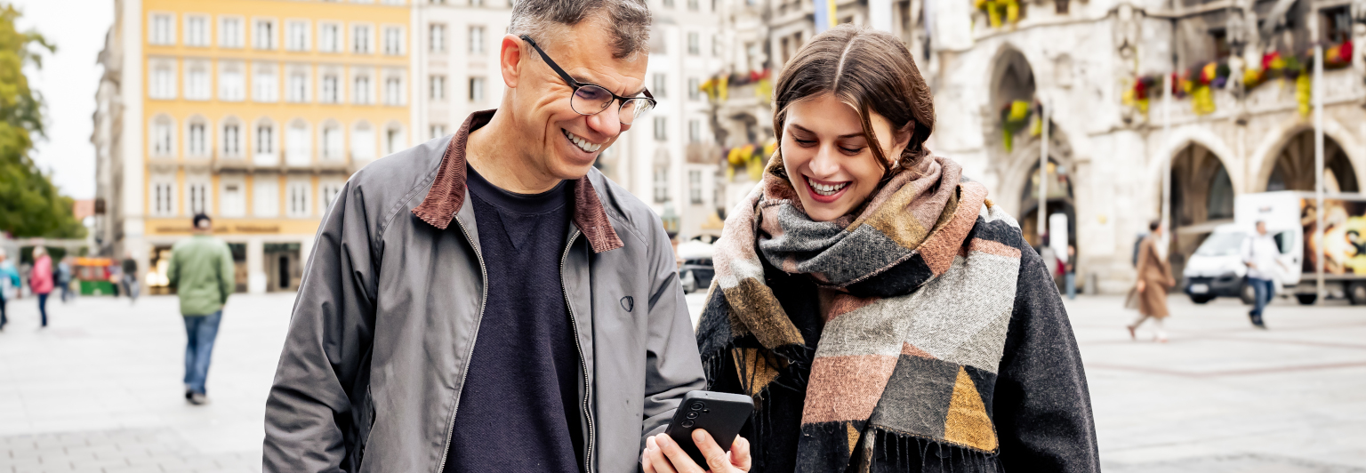 Mann und Frau auf dem Marienplatz im Gespräch und mit einem Handy