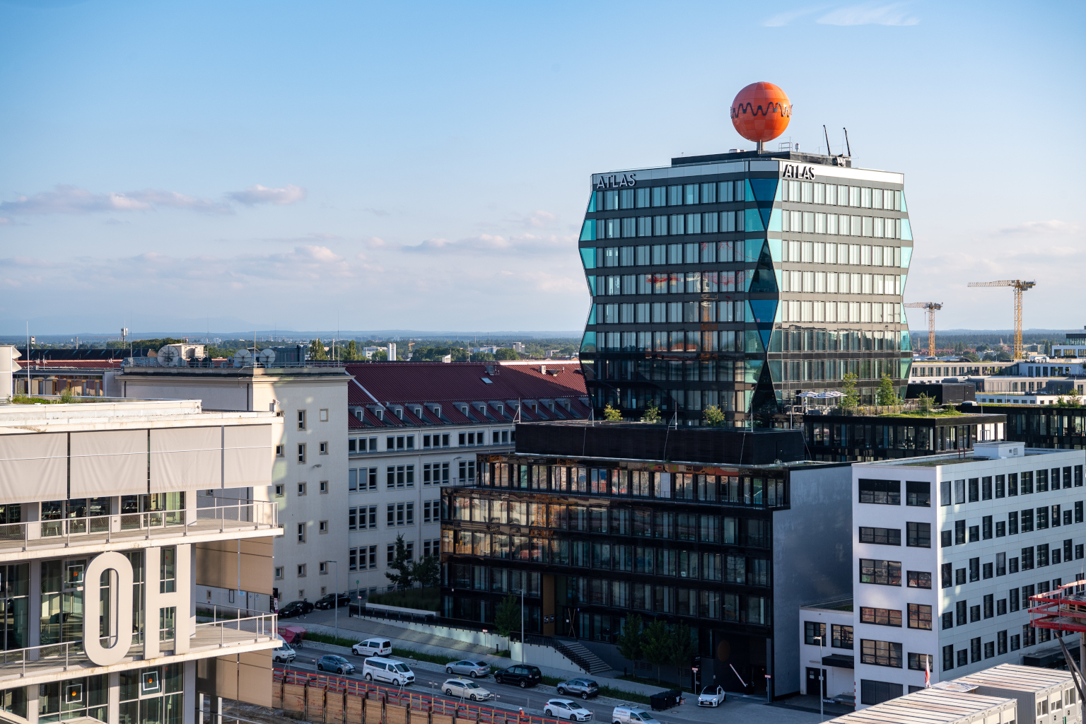 Blick auf neue Gebäude im Münchner Werksviertel, das Atlas Hochhaus mit der orangenen Kugel auf dem Dach und das Werk 12