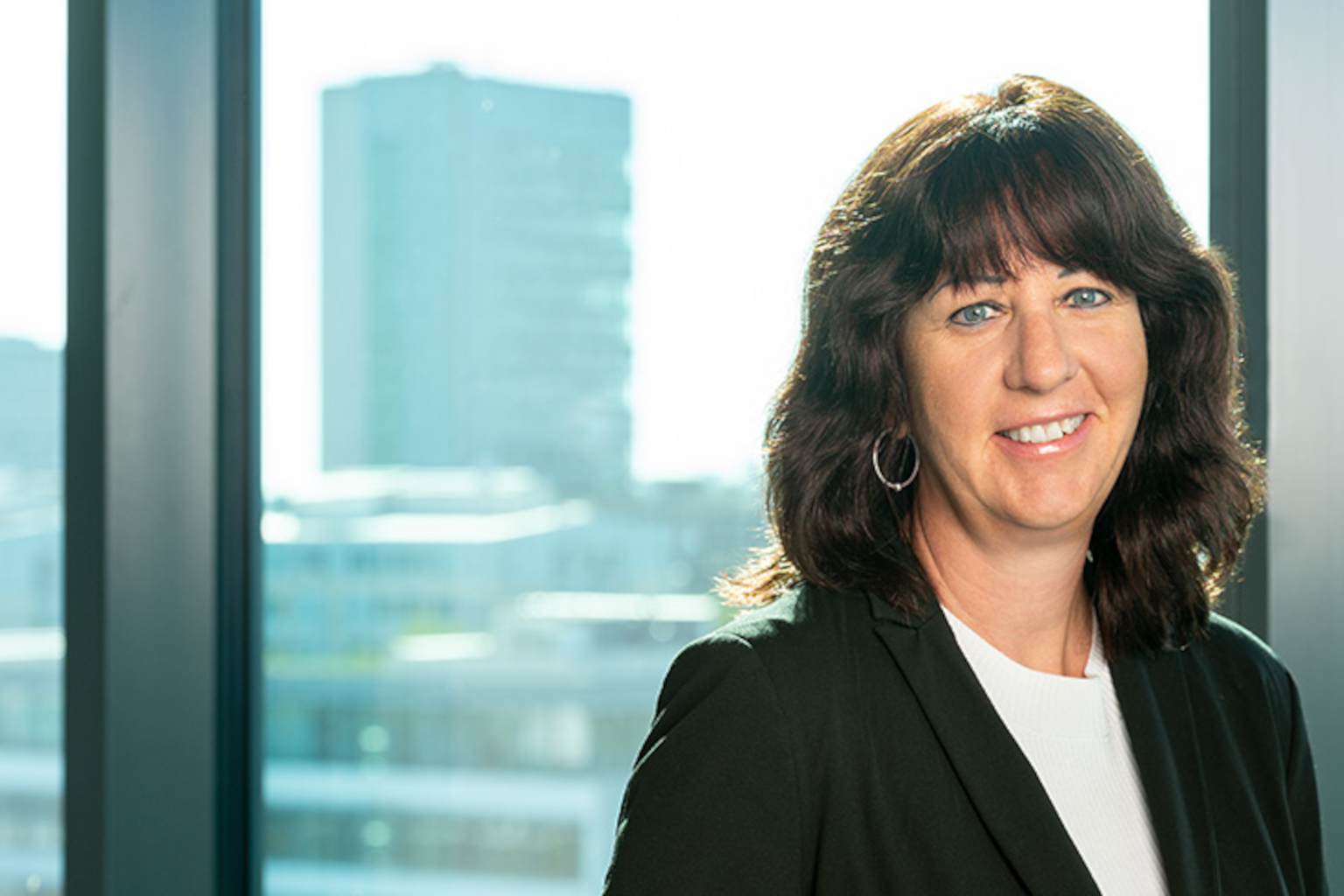 Weibliches Porträt vor Fenster, dahinter Hochhaus